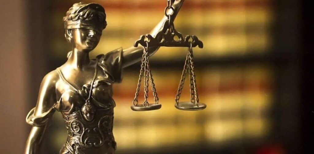 : Lady Justice holding scales in front of a blurred image of law books, symbolizing fairness and the legal process in court research and due diligence.